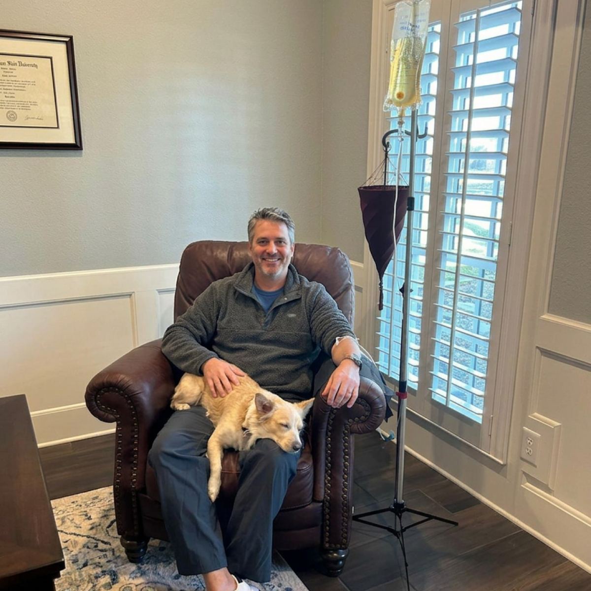 A client relaxing in a leather armchair with his dog during an in-home IV