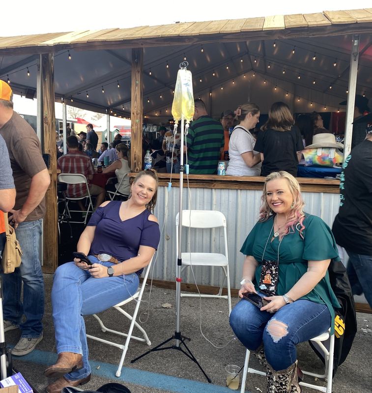 Two clients smiling at an outdoor bar during their IVs at an event