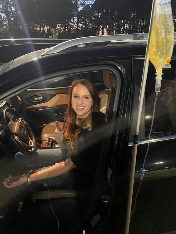 A client giving a thumbs up from her car during her IV
